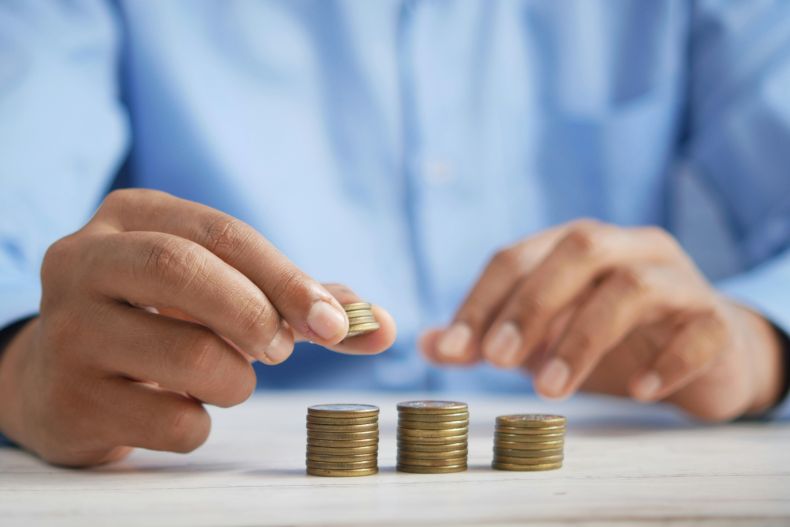 Person in a blue shirt stacks coins into 3 stacks.