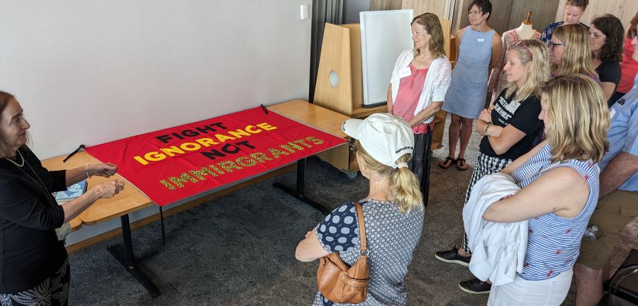 Teachers view a fabric sign that reads, "Fight Ignorance Not Immirgrance."