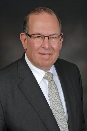 headshot of daniel alpert with glasses and in a suit