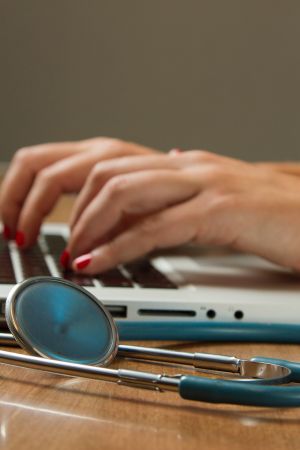 stethoscope next to computer that someone is typing on