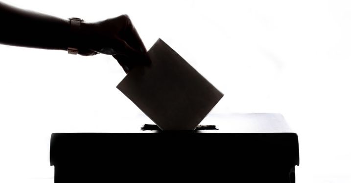 Hand placing ballot in voting box