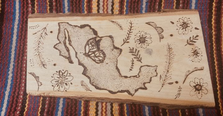 Wood carving of Latin America surrounded by plants and flowers.