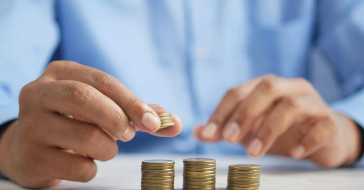 Person in a blue shirt stacks coins into 3 stacks.
