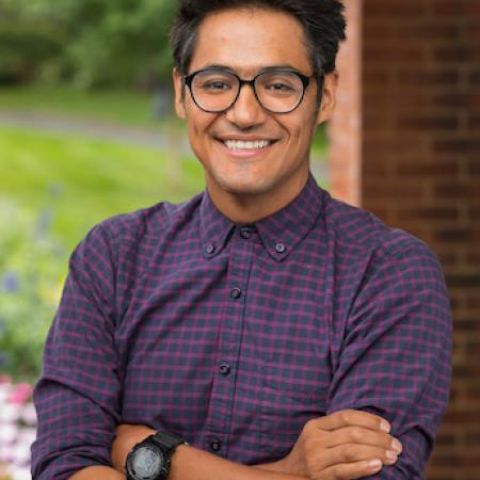 Juan Manuel Aldape Muñoz posing in front of brick wall and grass.