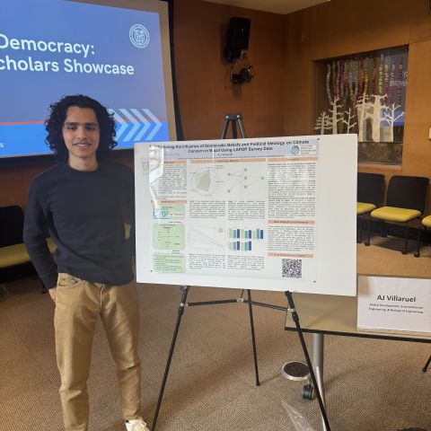 Global scholar smiles for a picture near a research poster.