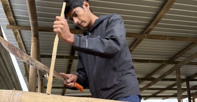 Laidlaw scholar uses a machete to cut a stick.